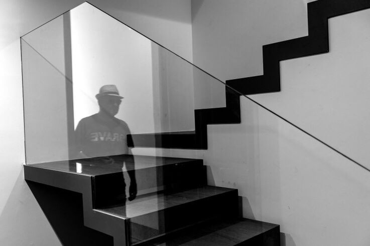 MAN STANDING BY STAIRCASE AGAINST BUILDING