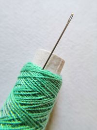 Close-up of green plastic bag on table against white background