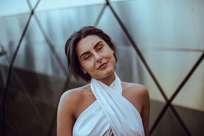 Beautiful young woman with eyes closed against fence