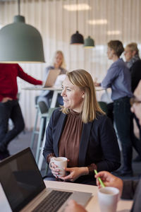 Smiling woman holding coffee mug during meeting