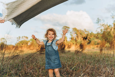 Cute red head 2 years old smiling girl under waving blanket