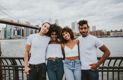 Portrait of friends standing by east river in city