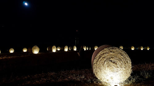 Illuminated lights on field against sky at night