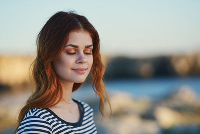 Portrait of smiling young woman against sky