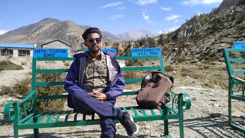 Full length portrait of young man sitting outdoors