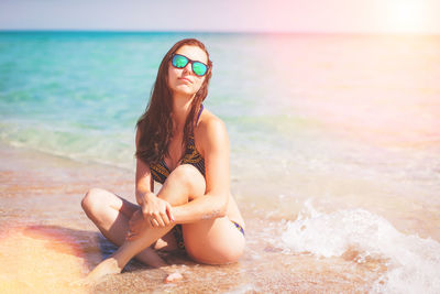 Young woman wearing sunglasses sitting on beach