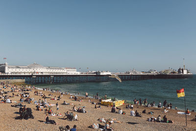 People at beach by palace pier against clear sky