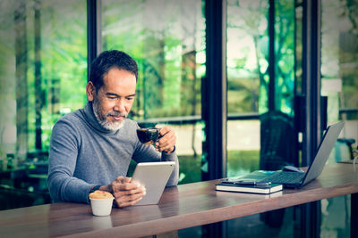 Man using phone while sitting on table