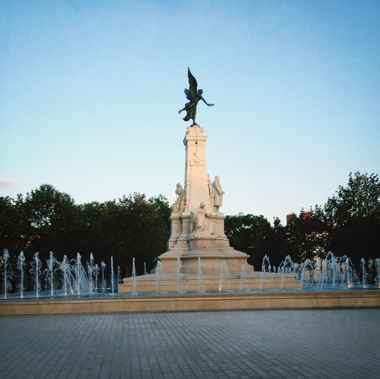 statue, art and craft, sculpture, human representation, art, creativity, clear sky, copy space, animal representation, built structure, famous place, architecture, monument, travel destinations, tree, fountain, blue, travel