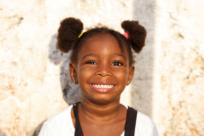 Portrait of smiling girl against wall