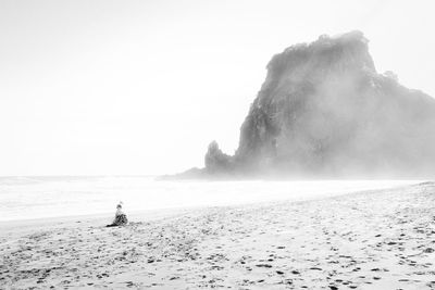 Rear view of people on beach against clear sky
