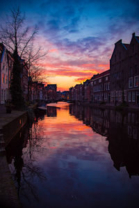 Canal amidst buildings against sky during sunset