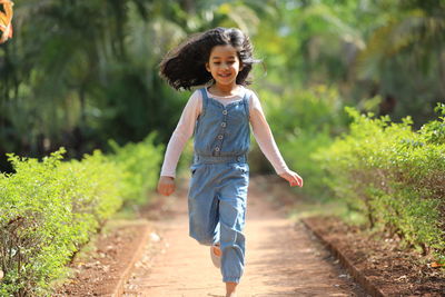 Smiling cute girl running on footpath