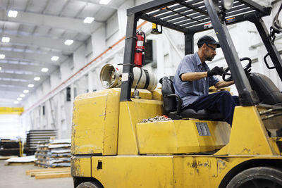 Male worker driving forklift in warehouse