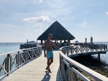 Man standing on pier over sea against sky