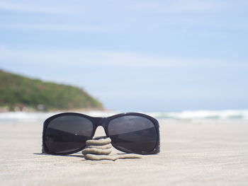 Sunglasses on beach against sky