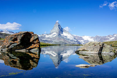 Scenic view of lake and mountains against blue sky