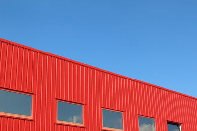 Low angle view of red building against clear blue sky