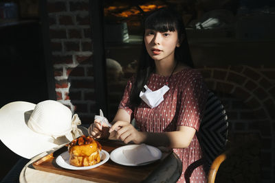 Young woman looking up while sitting on table at restaurant