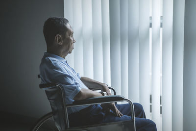 Thoughtful senior man sitting on wheelchair at home