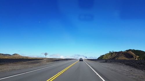 Road against clear blue sky