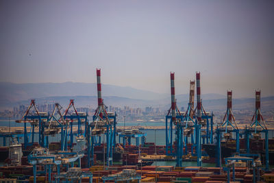 Cranes at harbor against sky