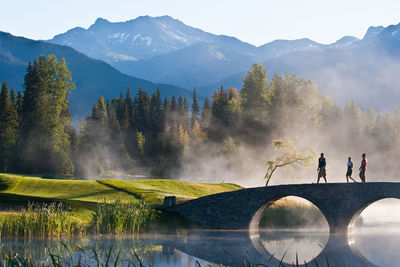 People on lake against mountain range