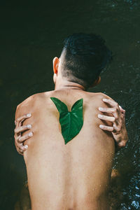 Rear view of naked man sitting by river