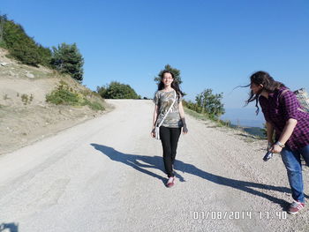 Woman walking on road against clear sky