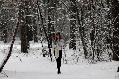 Portrait of woman standing on snow covered field against frozen trees