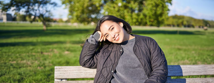 Portrait of young woman standing against trees