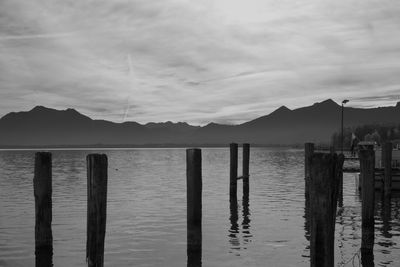 Wooden posts in sea against sky