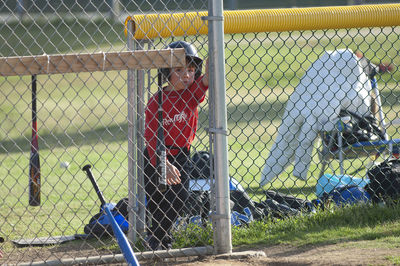 Rear view of man seen through chainlink fence