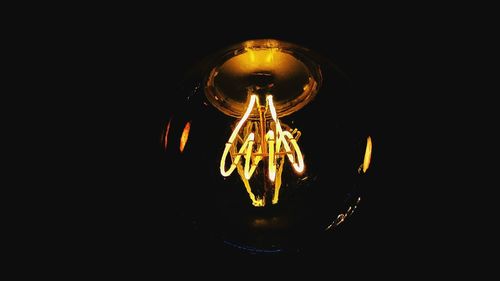 Close-up of illuminated light bulb against black background