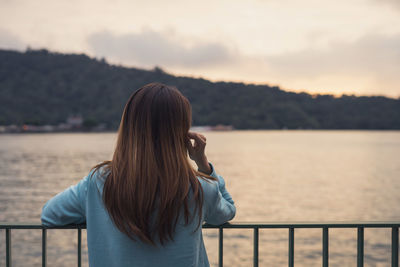 Rear view of woman looking at lake in forest