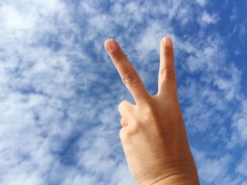 Low angle view of human hand against sky