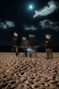 People on beach against sky at night