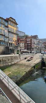 Canal by buildings in city against sky