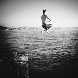 Woman jumping in sea against clear sky