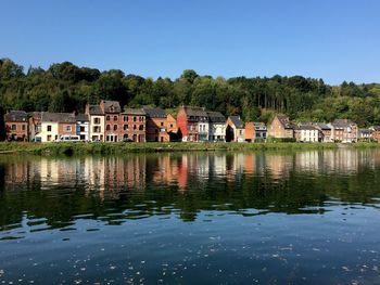 Lake by building against clear blue sky