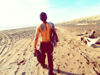 Rear view of man standing on beach against sky