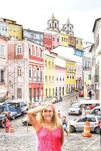 Portrait of smiling woman on street against buildings in city