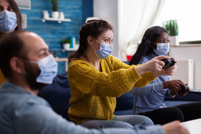 Cheerful people wearing mask playing game at home