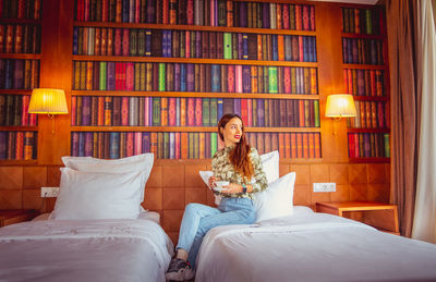 Young woman sitting on bed at home