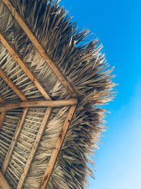 Low angle view of thatched roof against blue sky