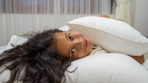 Portrait of young woman lying on sofa at home