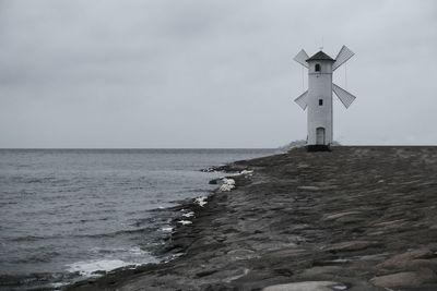 Lighthouse by sea against sky