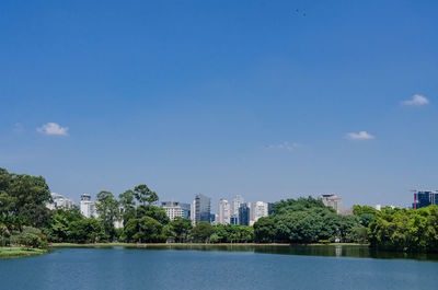 Scenic view of lake by buildings against blue sky
