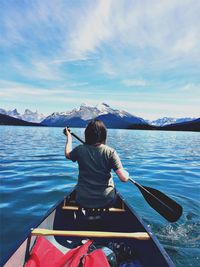 Rear view of person sailing on boat against mountain