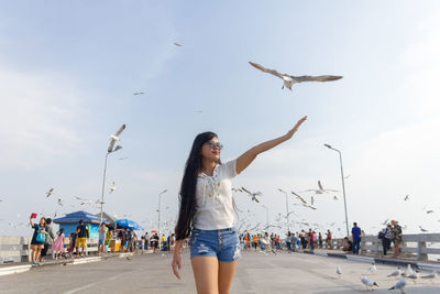 Woman gesturing while walking against sky